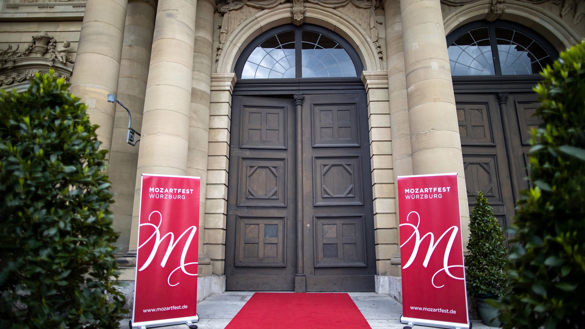 28.05.2021, Bayern, Würzburg: Zwei Aufsteller mit der Aufschrift "Mozartfest Würzburg" stehen an einem roten Teppich vor der Würzburger Residenz. Am Abend wurde das Mozartfest eröffnet. Foto: Daniel Karmann/dpa +++ dpa-Bildfunk +++