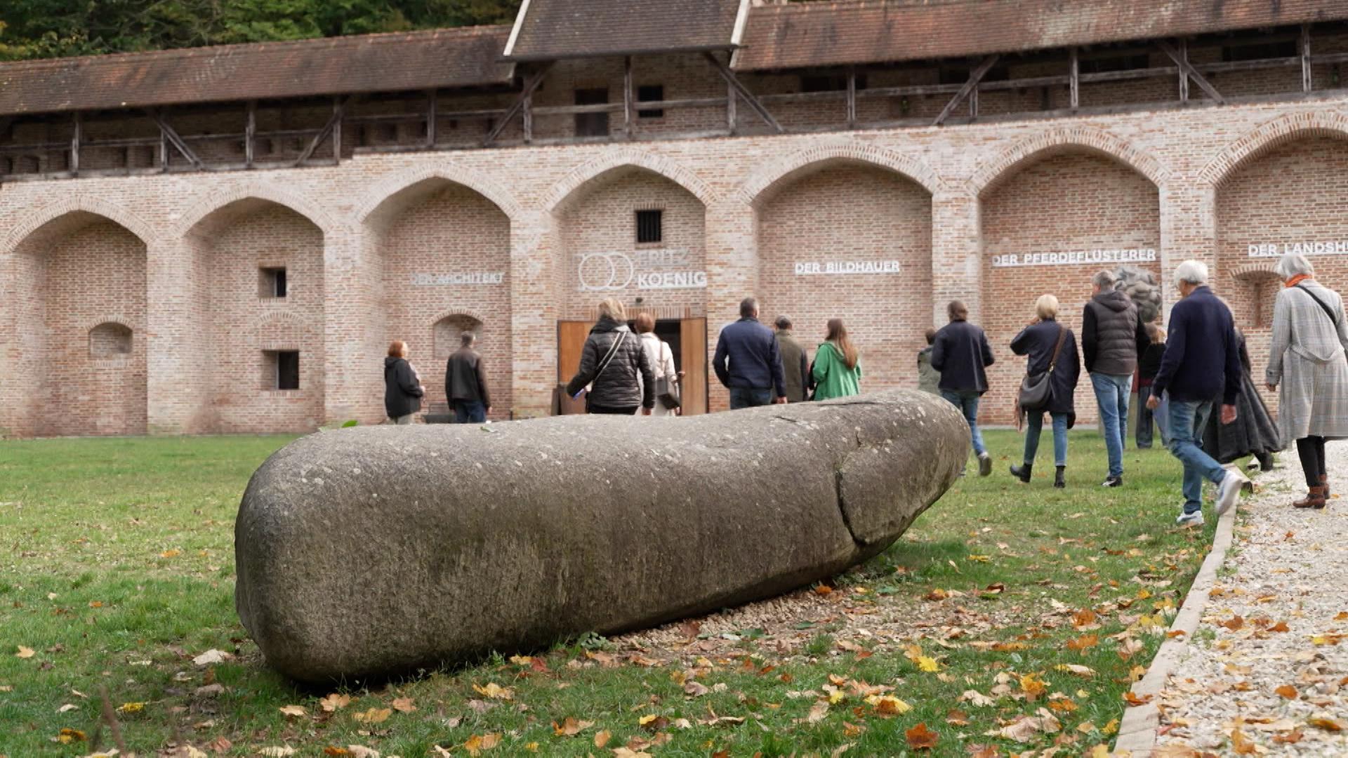 Besucher strömen in eine Ausstellung des Künstlers Fritz Koenig in Landshut.