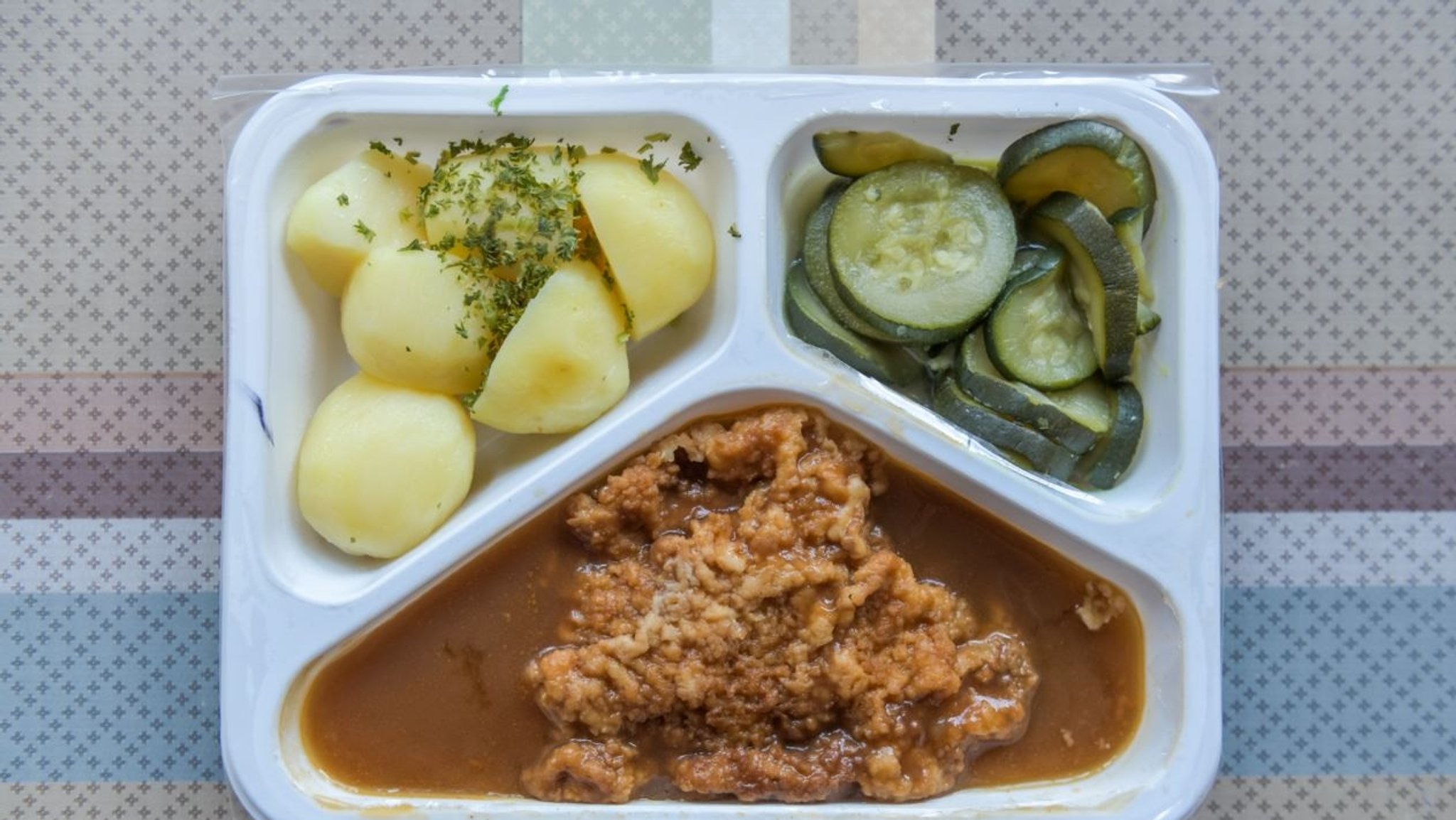 Ein Fertiggericht mit Kartoffeln, Schnitzel und Gurken (Symbolbild)