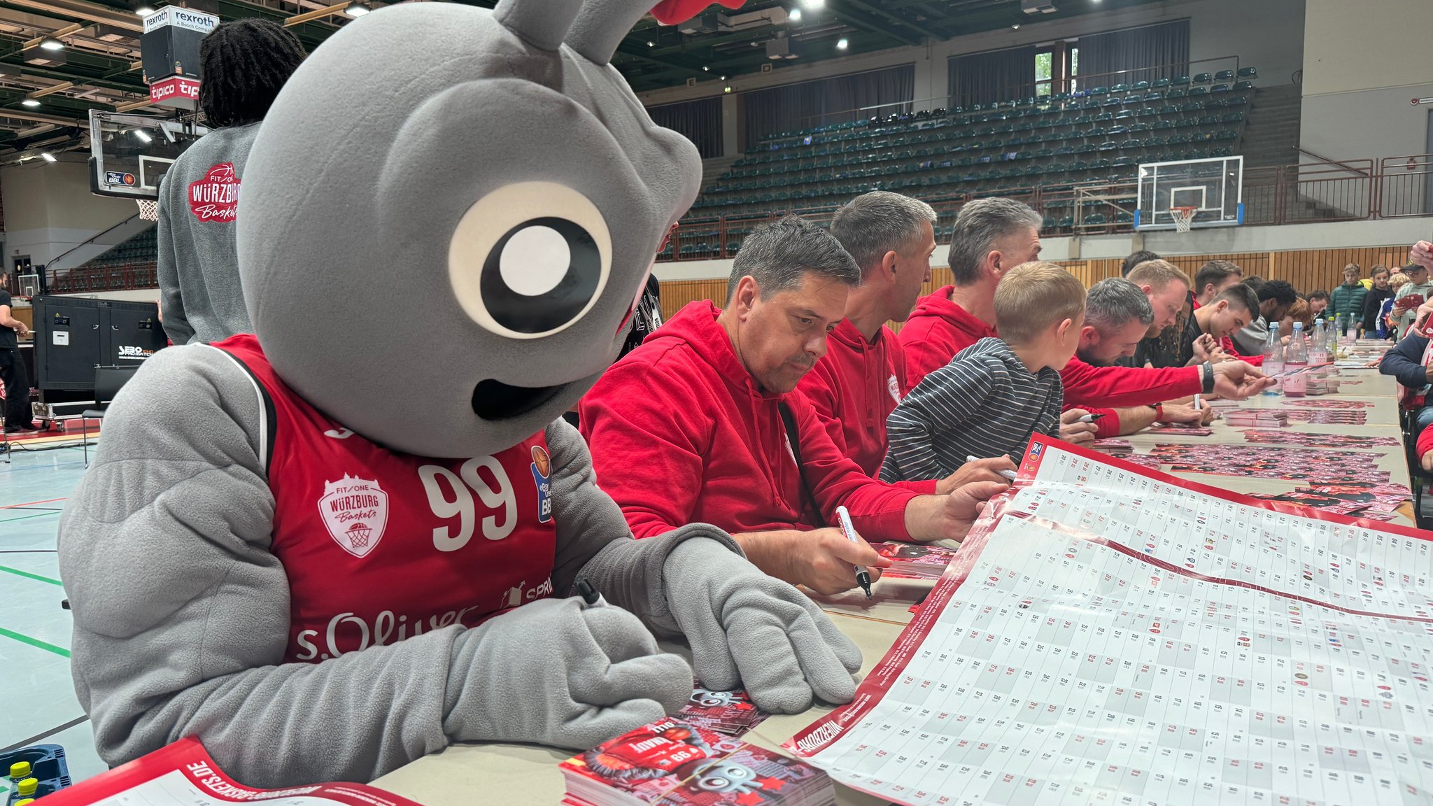 Würzburg Baskets' Maskottchen Olli signiert fleißig Autogrammkarten – der Andrang ist groß. Er symbolisiert übrigens einen Röntgenstrahl