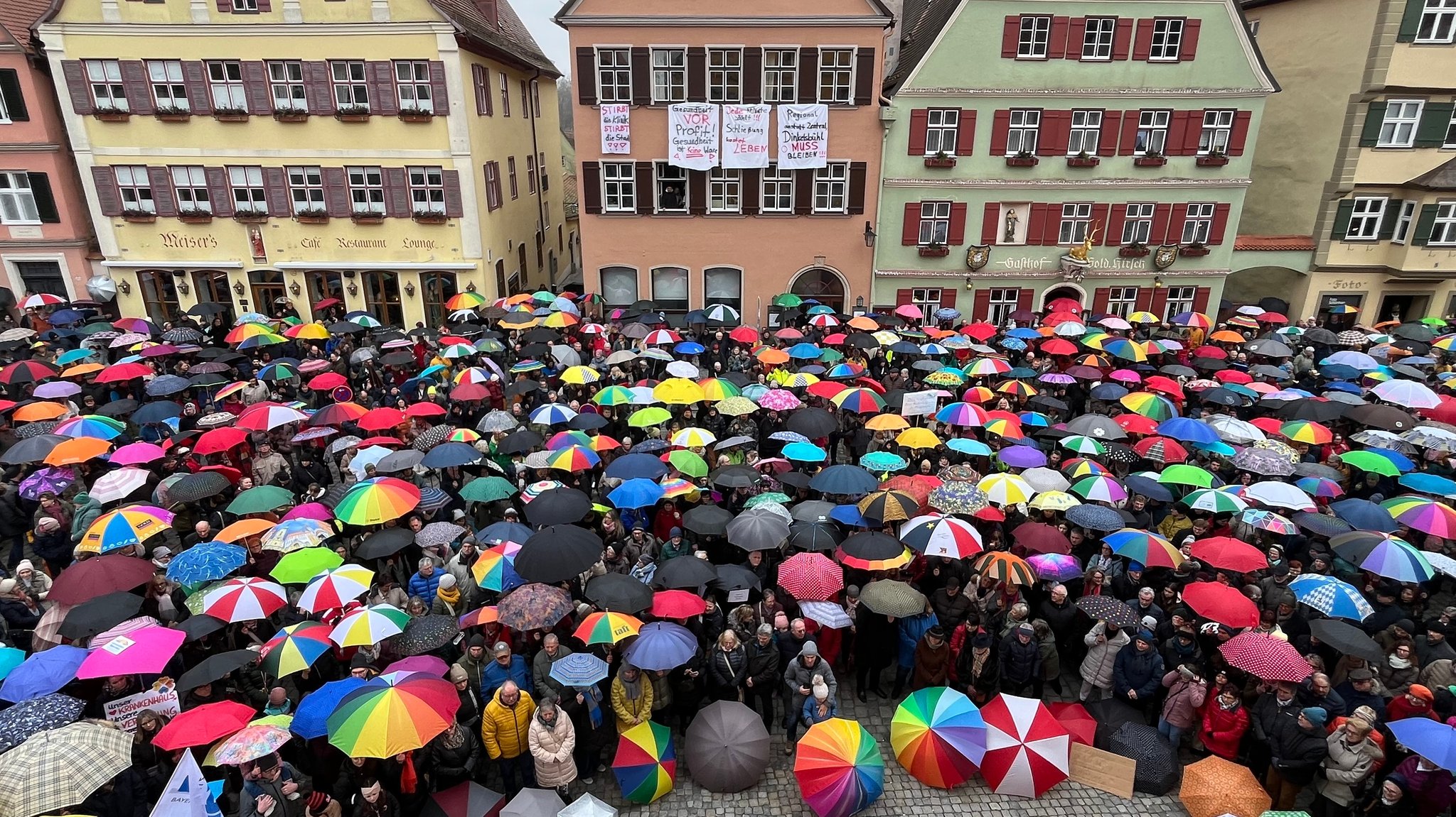 Teilnehmende spannen ihre Regenschirme auf.