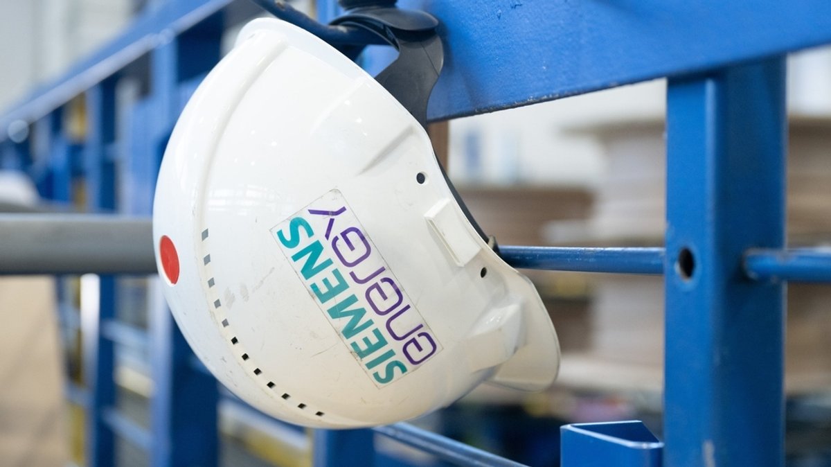 Ein Schutzhelm mit der Aufschrift "Siemens Energy" hängt in einer Werkhalle im Transformatorenwerk Siemens Energy.