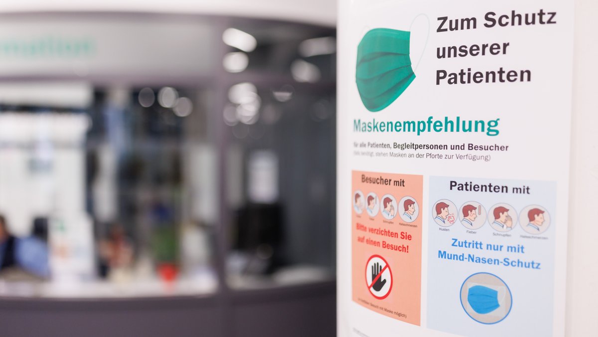Am Eingangsbereich am Uniklinikum Erlangen weist ein Plakat auf eine "Maskenempfehlung" für alle hin.