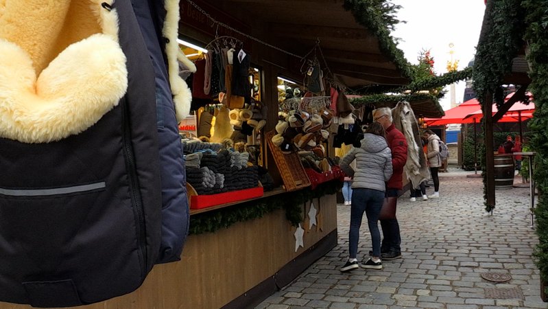 Besucher stehen am Christkindlmarkt in Straubing an einem Warenstand.