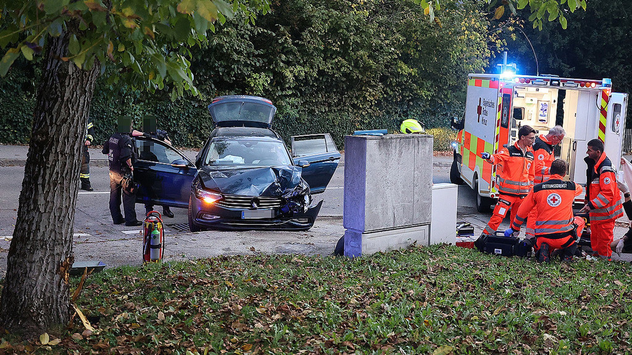 Polizei und Rettungskräfte stehen am und neben dem Unfallfahrzeug.