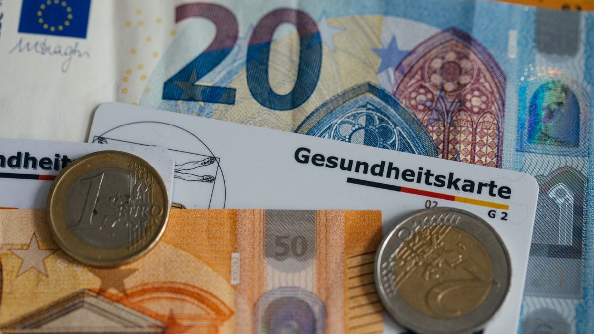 Geldscheine und Münzen, zwischen denen eine Kassen-Chipkarte liegt