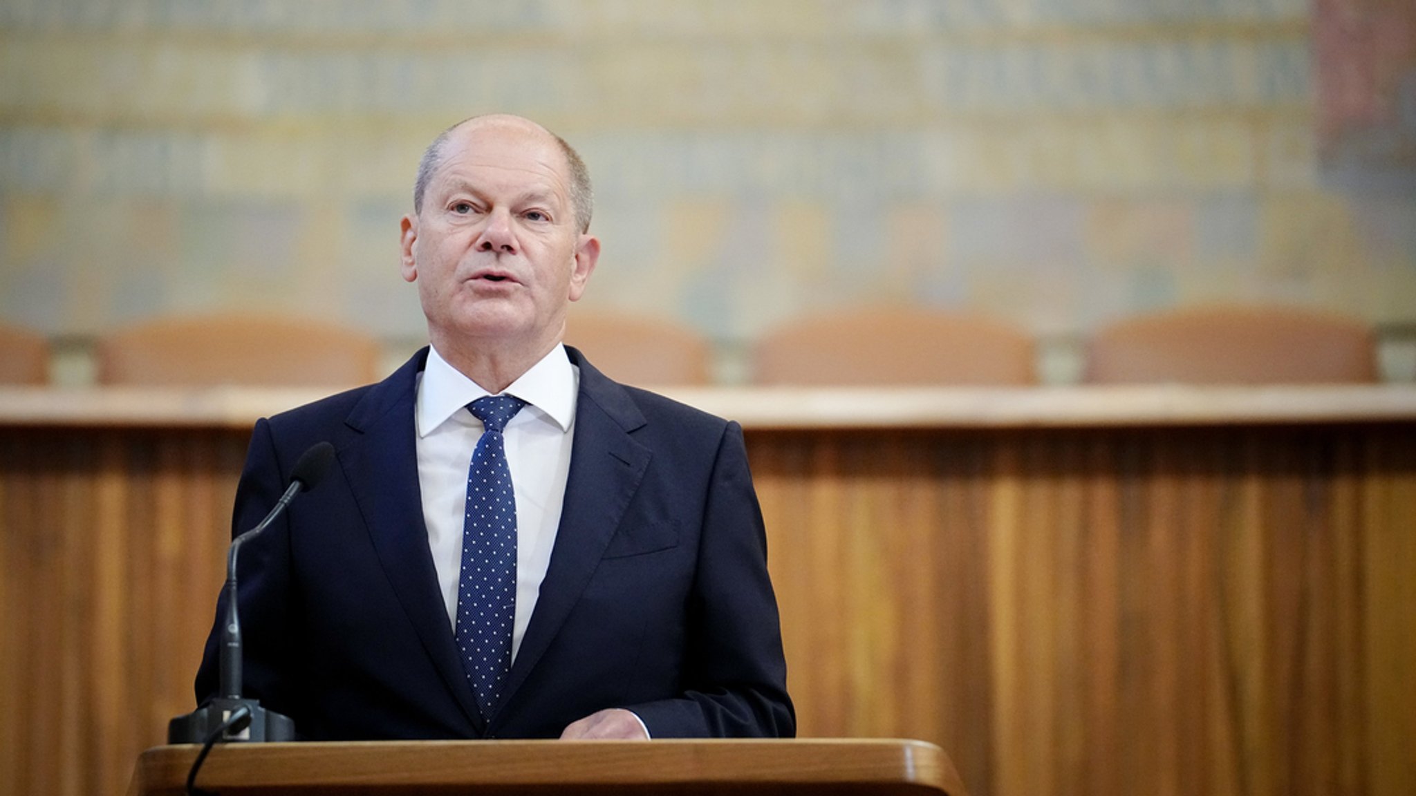 Bundeskanzler Olaf Scholz hält an der Karls-Universität eine Rede. Er steht an einem Rednerpult.