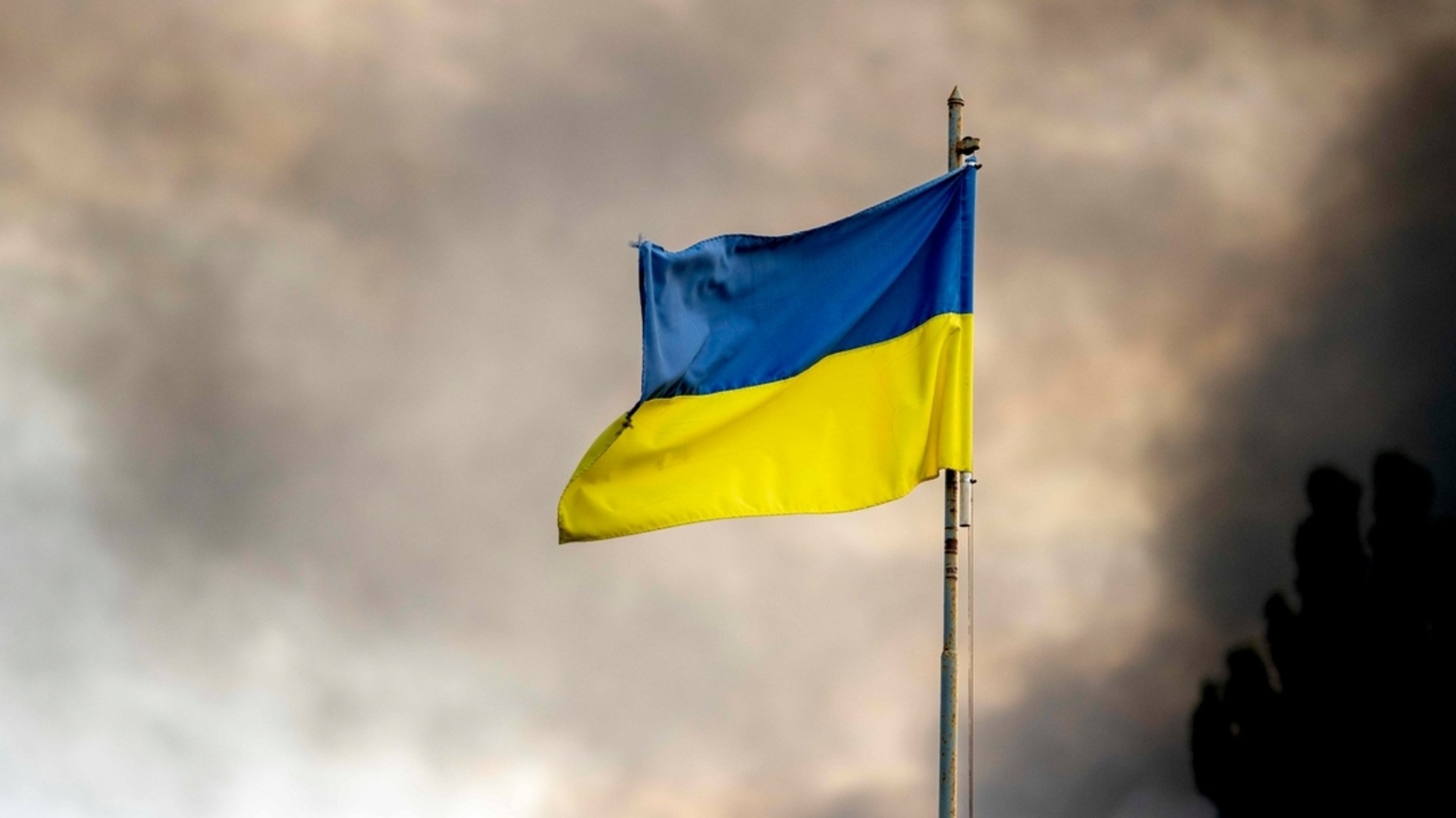 Die ukrainische Flagge ist vor dem Rauch eines Feuers zu sehen, nach Angriffen auf die Ukraine über Kiew. (Archivbild vom 2.9.24)