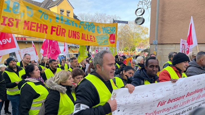 Menschen in gelben Streikwesten, mit Fahnen und Plakaten laufen durch Erlangen.