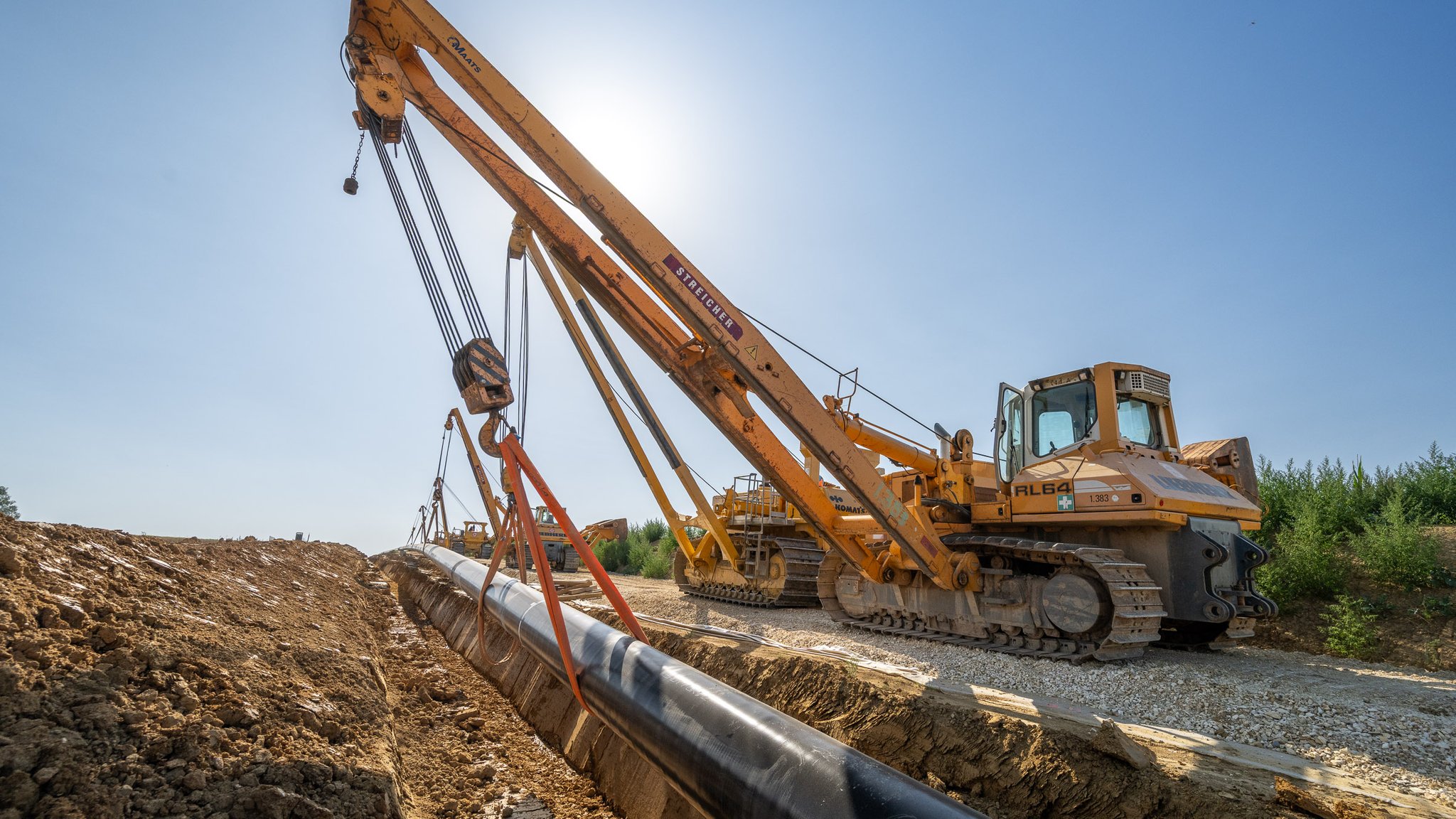 Kräne verlegen die Rohre in der Erde. 