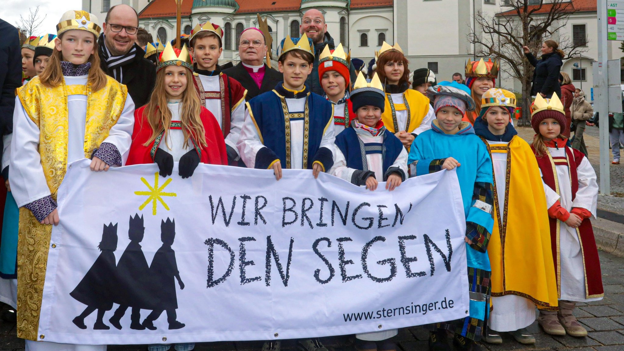 Sternsinger in Kempten. Sie tragen ein Transparent, auf dem "Wir bringen den Segen" steht.