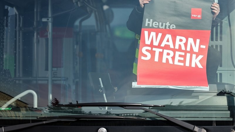 (Symbolbild) Ein Mitarbeiter befestigt während eines Warnstreiks ein Plakat in einem Bus auf einem Betriebshof. | Bild: dpa-Bildfunk/Jan Woitas (Symbolbild) Ein Mitarbeiter befestigt während eines Warnstreiks ein Plakat in einem Bus auf einem Betriebshof.