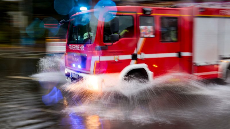 Ein Feuerwehrauto pflügt in Flensburg durch die Wassermassen der Sturmflut.