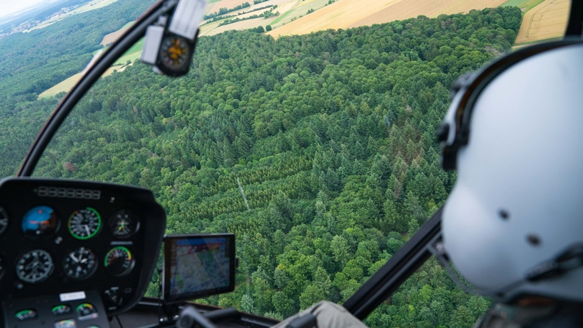 Ein Helikopterpilot fliegt über ein Waldgebiet (Symbolbild)