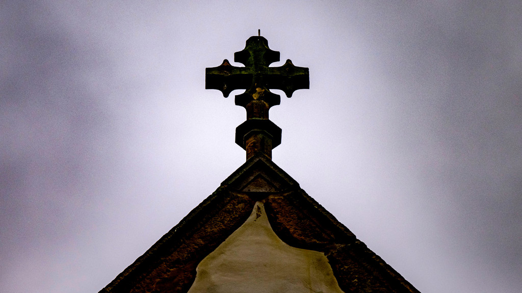 Der Blick auf das Kreuz einer Kirche im Regenwetter.