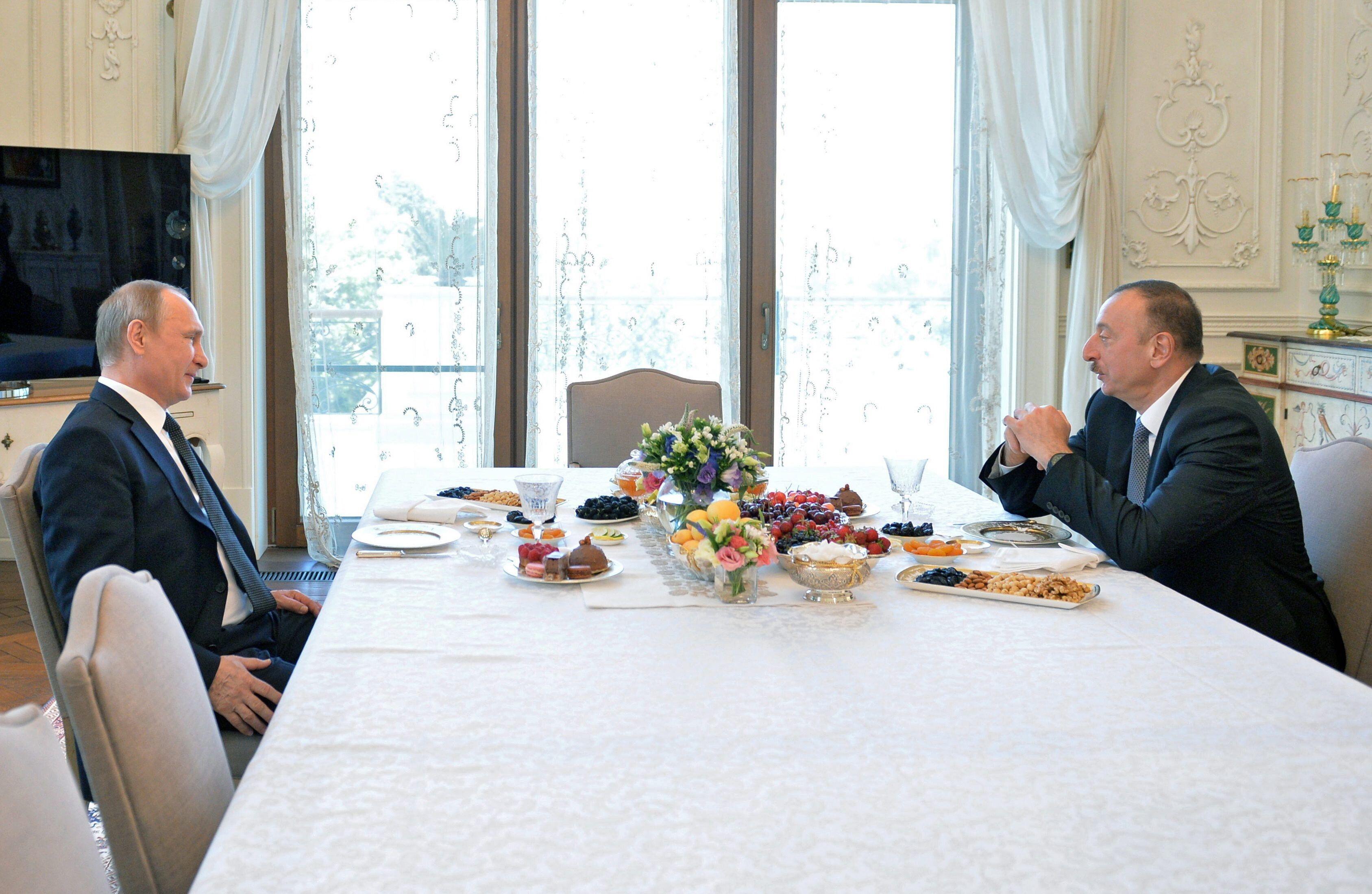 Die beiden Politiker sitzen an einer reich gedeckten Tafel 