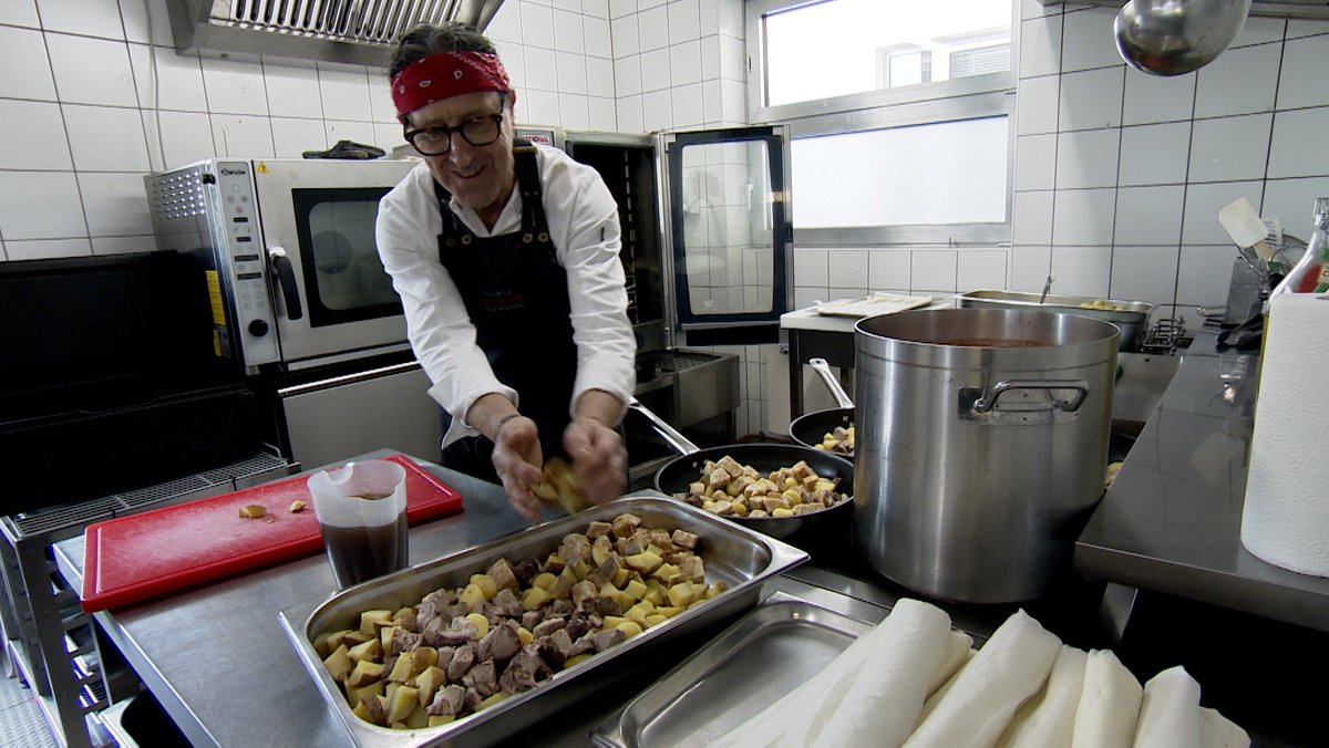 Ein Mann bereitet in einer Küche Essen zu.
