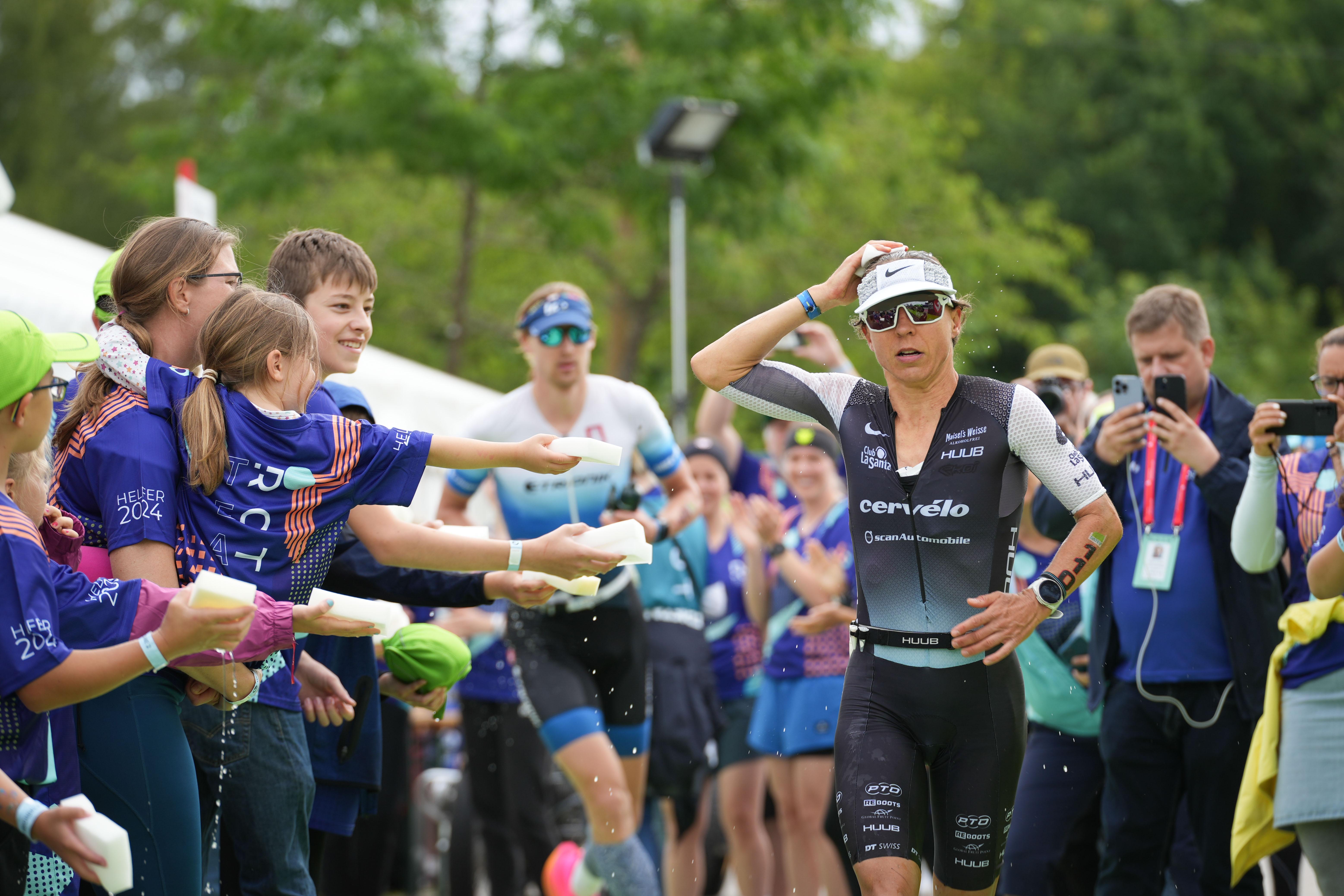 Helfer reichen Anne Haug kühlende Schwämme auf der Laufstrecke in Roth.