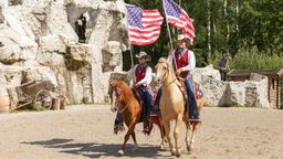 Reiter mit Pferden und amerikanischen Flaggen | Bild:Pullman City