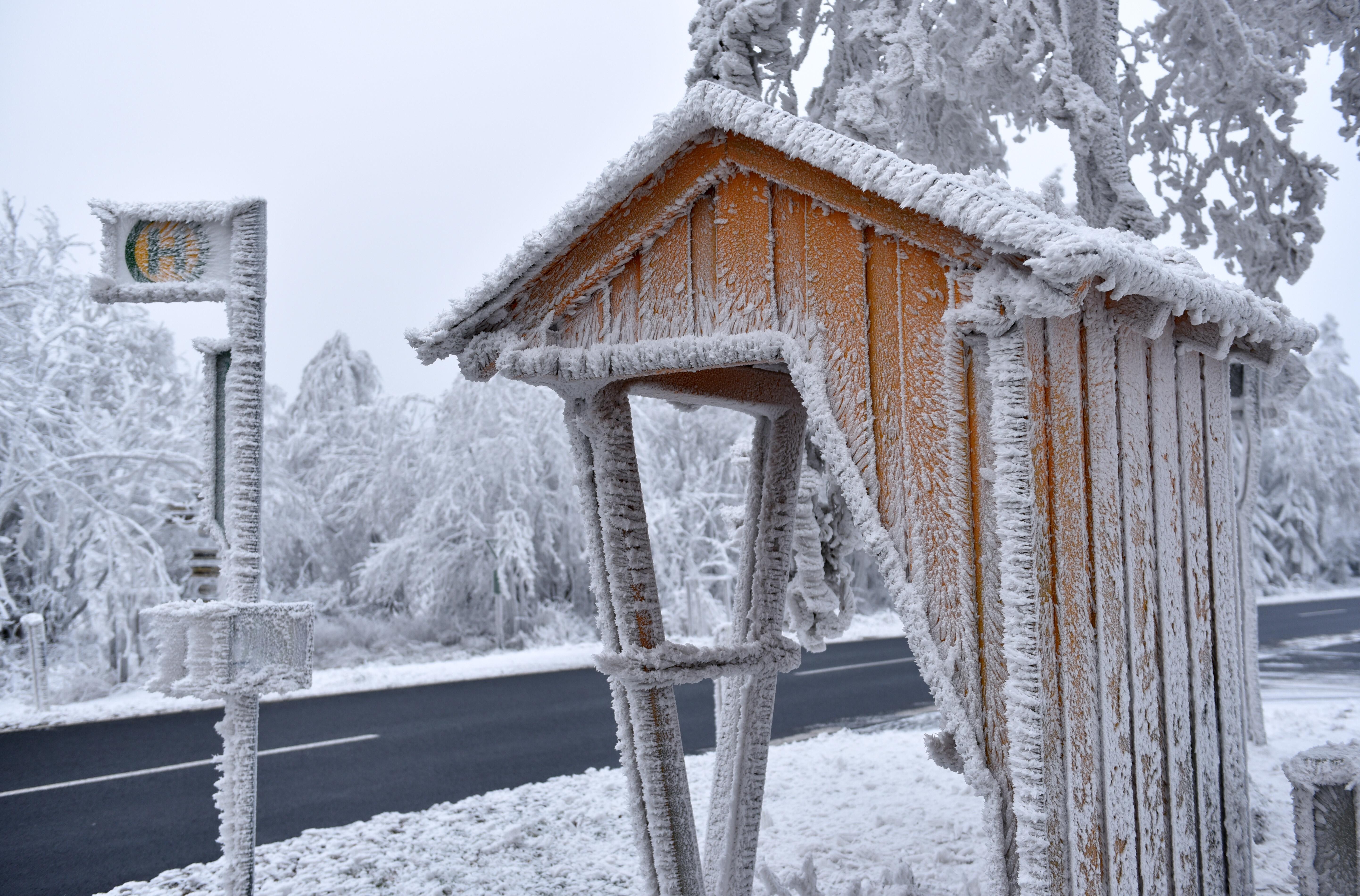 Bushaltestelle auf dem Land mit vereistem Haltestellenschild und Wartehäuschen (Symbolbild)