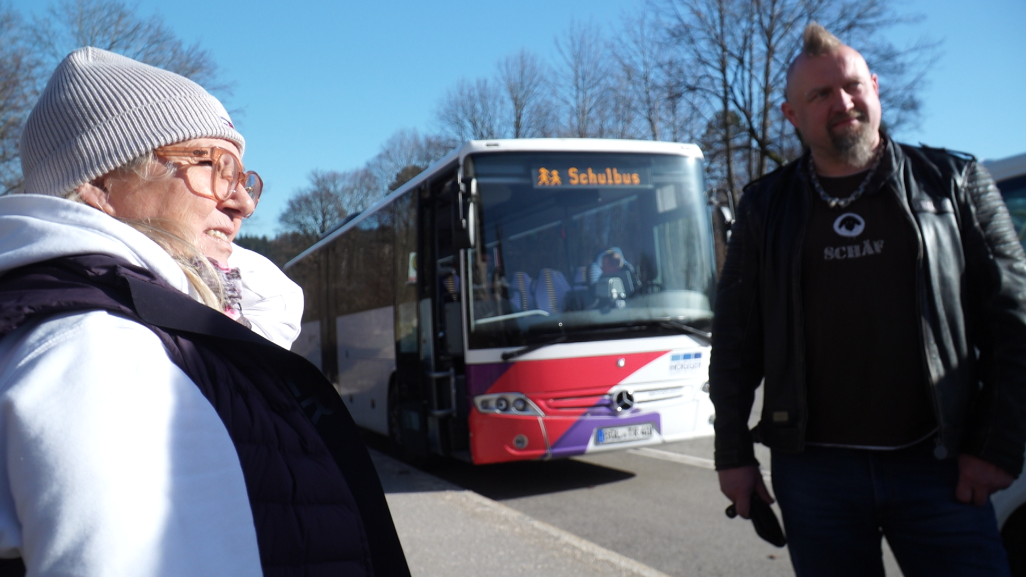 Eine Schulbusfahrerin und ein Schulbusfahrer warten in der Parkbucht auf die Kinder, um sie nach Hause zu bringen