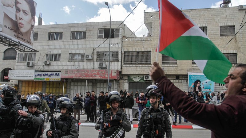 In Huwara im Westjordanland hält ein palästinensischer Demonstrant vor einer Reihe israelischer Soldaten eine palästinensische Flagge hoch. (Archivbild)