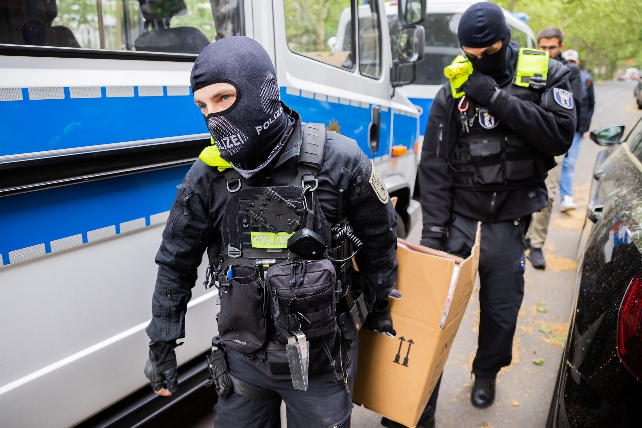 24.05.2023, Berlin: Polizisten tragen bei einer Hausdurchsuchung in Berlin-Kreuzberg einen Karton zu einem Fahrzeug. Polizei und Staatsanwaltschaft haben im Zuge eines Ermittlungsverfahrens zu Mitgliedern der Letzten Generation 15 Objekte in sieben Bundesländern durchsucht. 