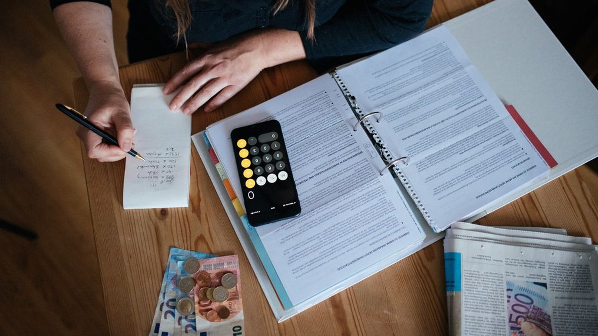 Person sitzt am Schreibtisch und prüft ihre Finanzen (Symbolbild).