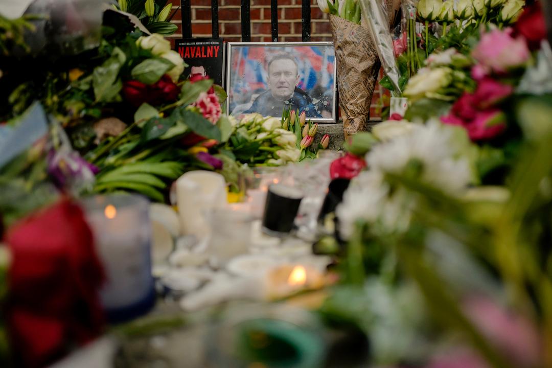 17.02.2024, Großbritannien, London: Ein Porträt von Alexej Nawalny ist zwischen Blumen und Kerzen vor der russischen Botschaft in London zu sehen.