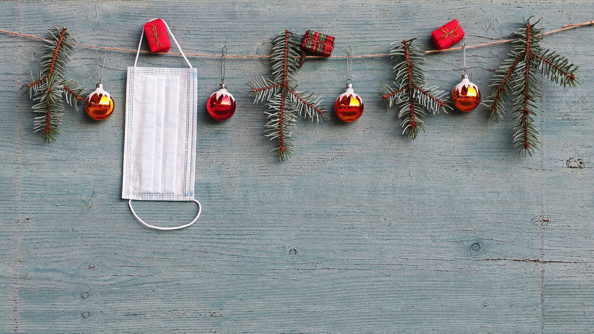 Adventskette mit Zweigen, Christbaumkugeln und einer aufgehängten Mund-Nasen-Maske.