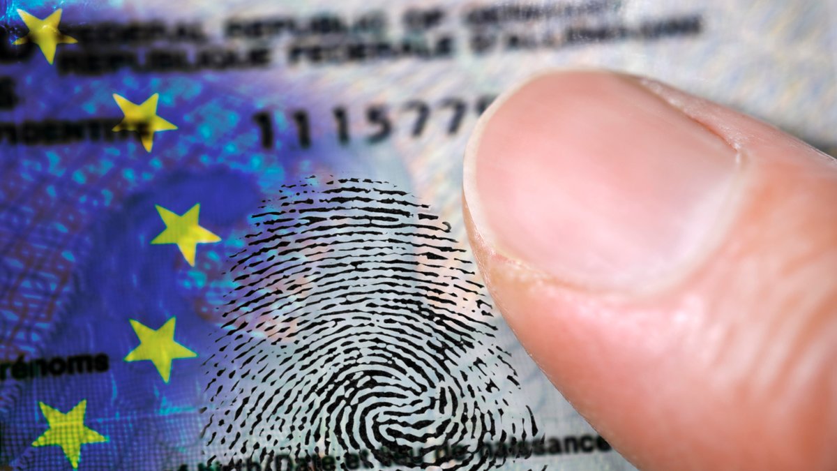 FOTOMONTAGE, Finger auf deutschem Personalausweis mit EU-Fahne und Fingerabdruck