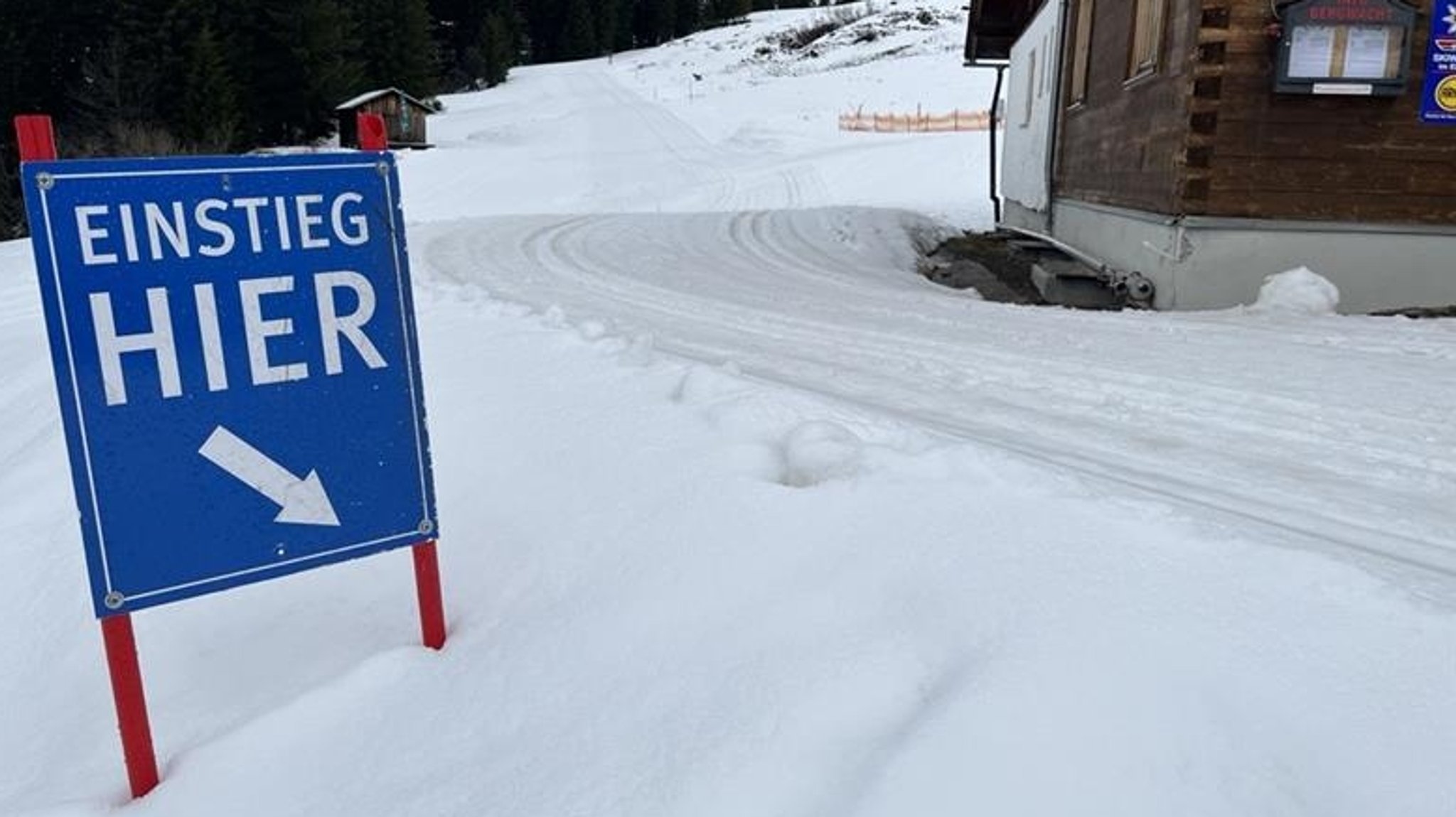 Ein blaues Schild mit der Aufschrift "Einstieg hier" markiert den Start zur Langlaufloipe bei Grasgehren.