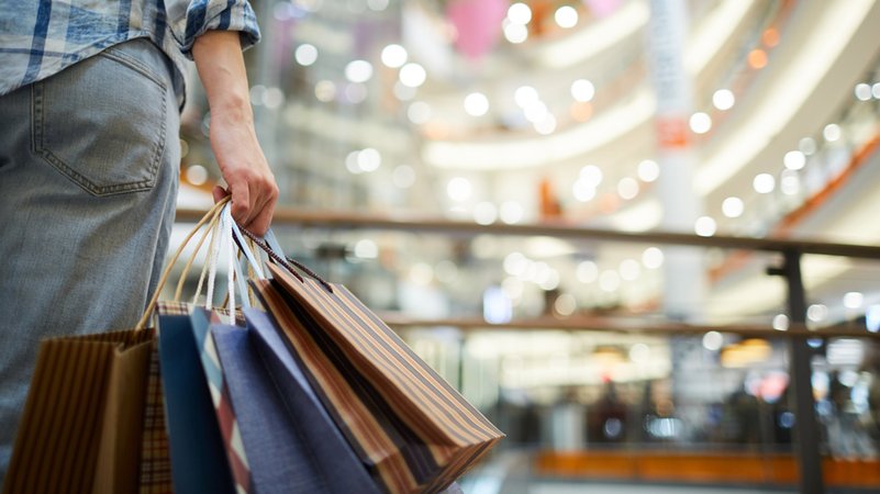 Symbolbild: Eine Person hält viele Einkaufstaschen in einem Einkaufszentrum. | Bild: stock.adobe.com/Seventyfour Symbolbild: Eine Person hält viele Einkaufstaschen in einem Einkaufszentrum.