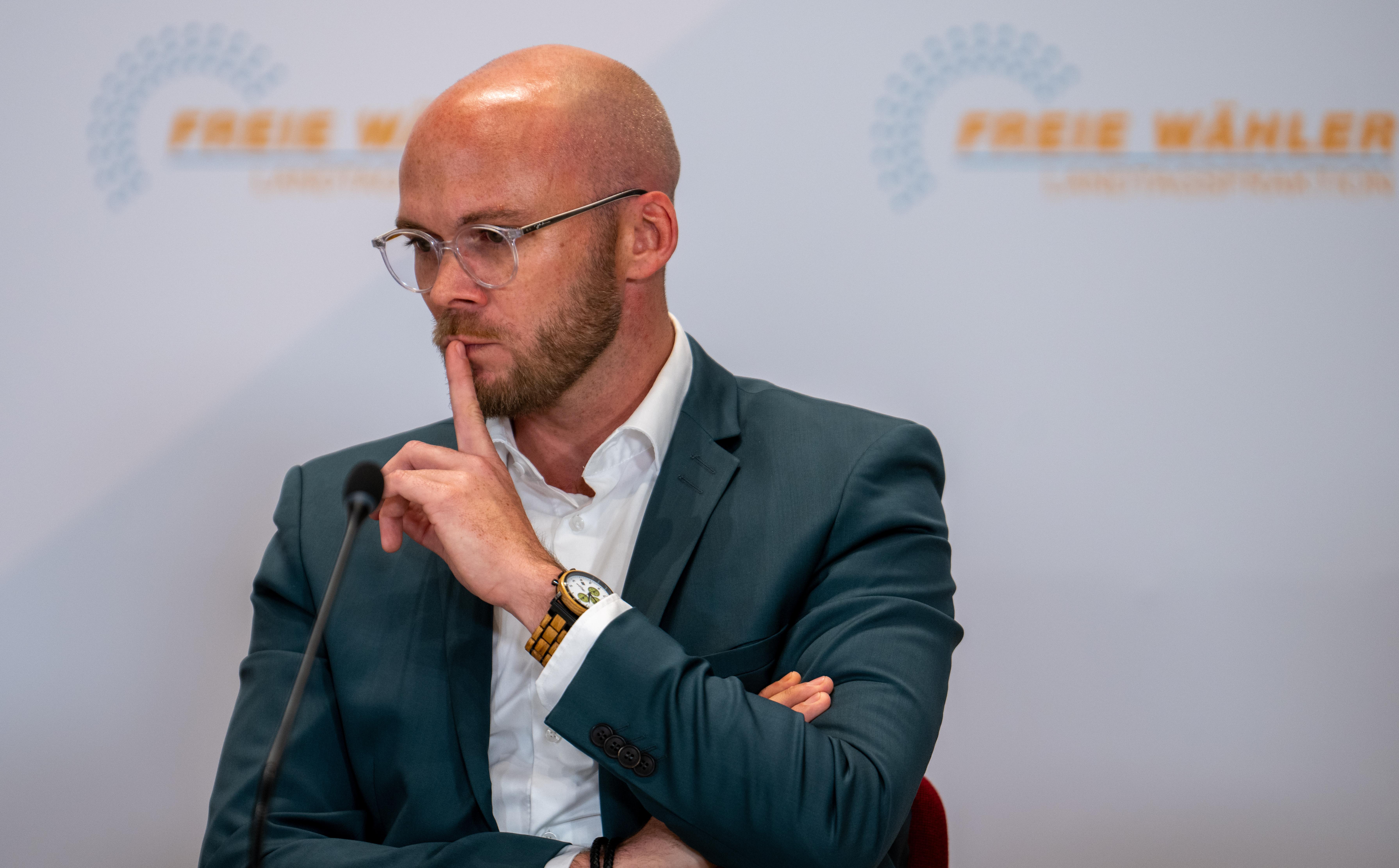 Freie-Wähler-Politiker Fabian Mehring hält sich den Zeigefinger an den Mund