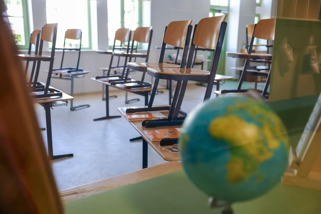 Blick in ein leeres Klassenzimmer, die Stühle stehen auf den Tischen. Im Vordergrund in Unschärfe ein Globus. Wegen der Störung an der Heizungsanlage fällt in einer Schule in Lauf an der Pegnitz der Präsenzunterricht teilweise aus. (Symbolbild)