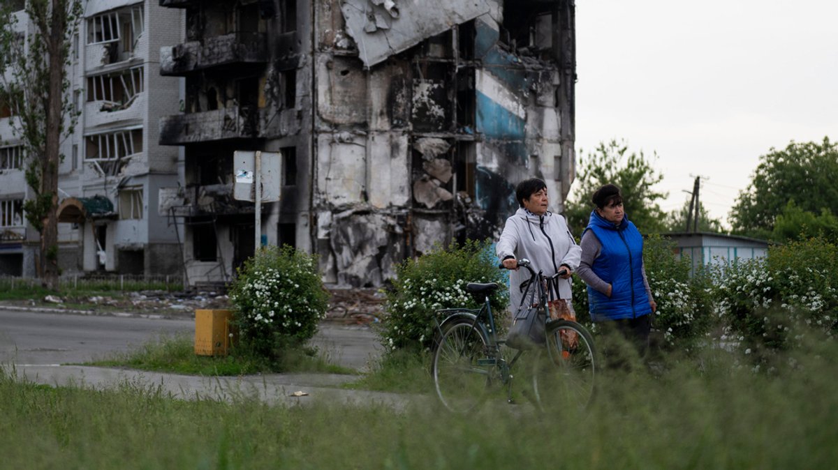 Zwei Frauen gehen an zerstörten Gebäuden in Borodjanka vorbei.