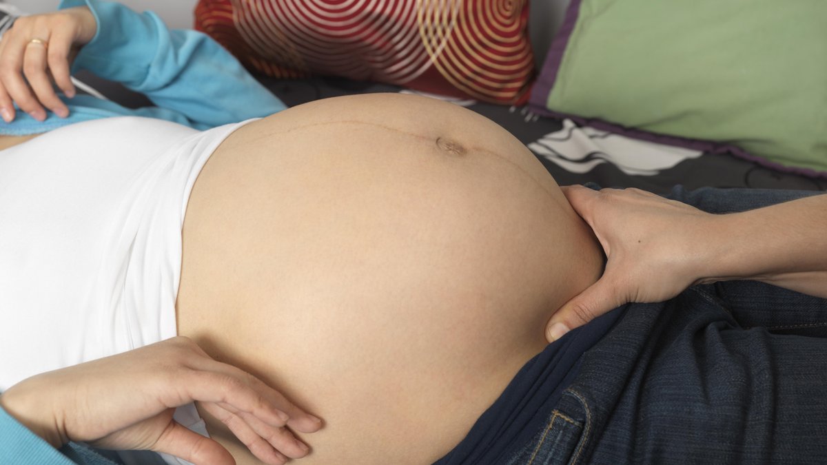 Schwangere Frau wird von einer Hebamme untersucht.