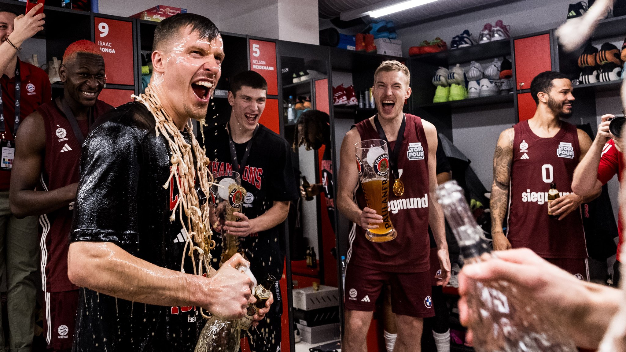 Andreas Obst (vorne), Niels Giffey (2.v.r.) und Nick Weiler-Babb (r.) nach dem Pokalsieg in der Kabine