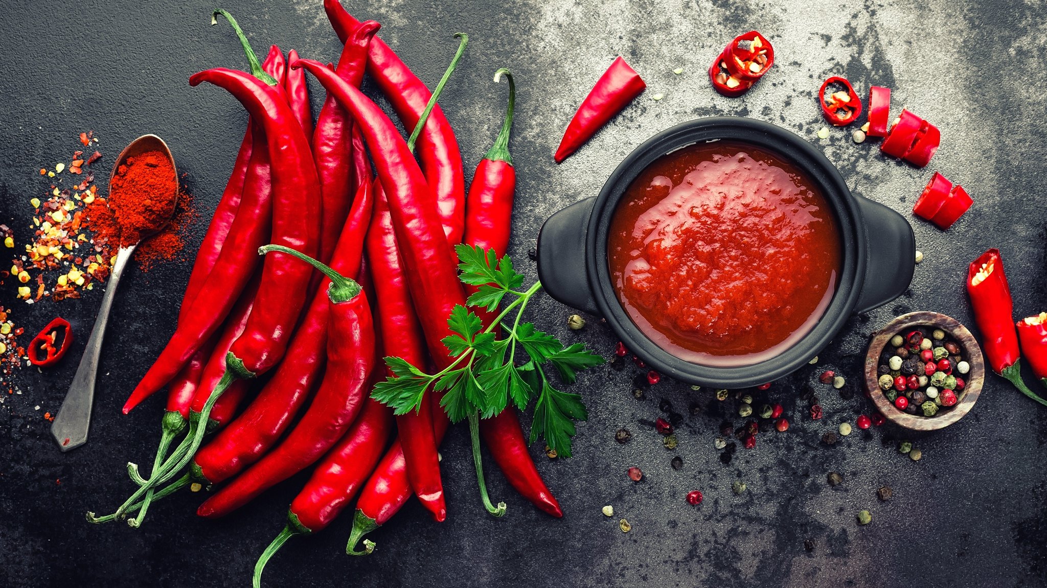 Flatlay von Chili Sauce mit Chilis und Pfeffer.