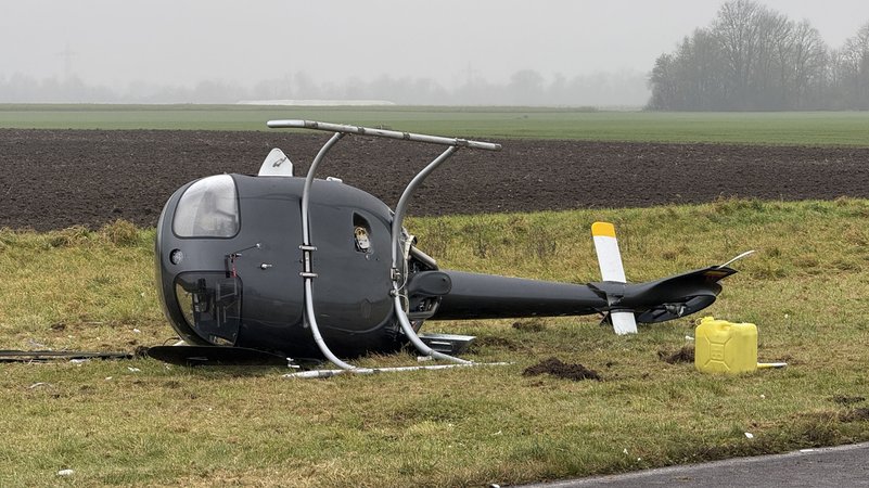 Ein abgestürzter Hubschrauber liegt auf der Seite auf einer Wiese. | Bild: Vifogra Ein abgestürzter Hubschrauber liegt auf der Seite auf einer Wiese.