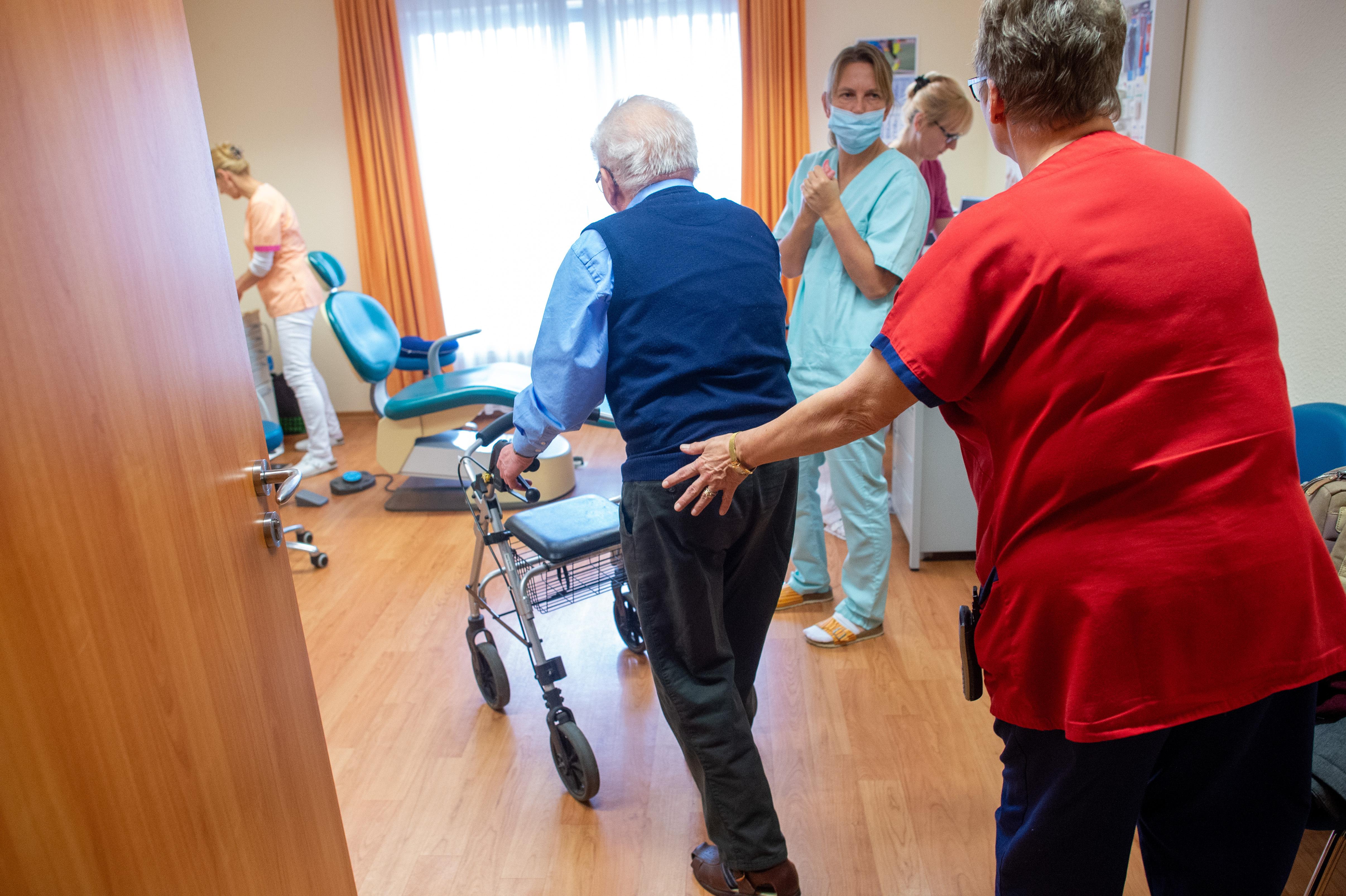 Ein älterer Herr kommt mit seinem Rollator in ein Behandlungszimmer