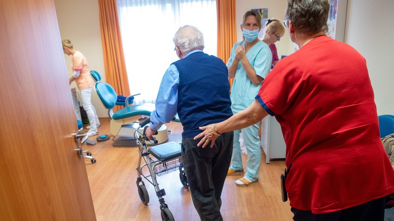 Ein älterer Herr kommt mit seinem Rollator in ein Behandlungszimmer