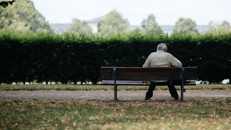 Ein Mann sitzt einsam auf einer Parkbank.