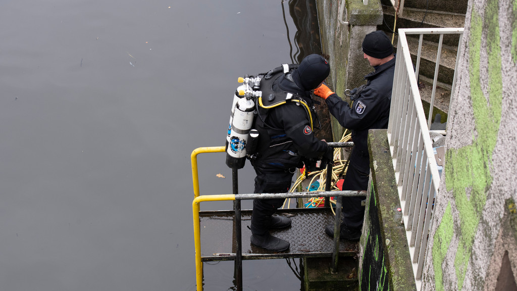 26.12.2022: Ein Polizeitaucher bereitet sich mit Hilfe eines Kollegen an einem Kanal an der Treptower Straße auf einen Einsatz vor. 