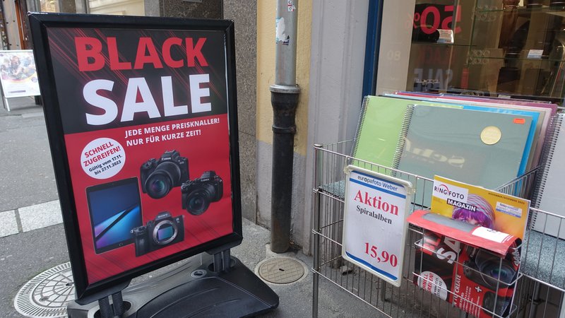 Mit knalligen Werbetafeln locken Einzelhändler in der Würzburger Innenstadt am Black Friday Kunden an.