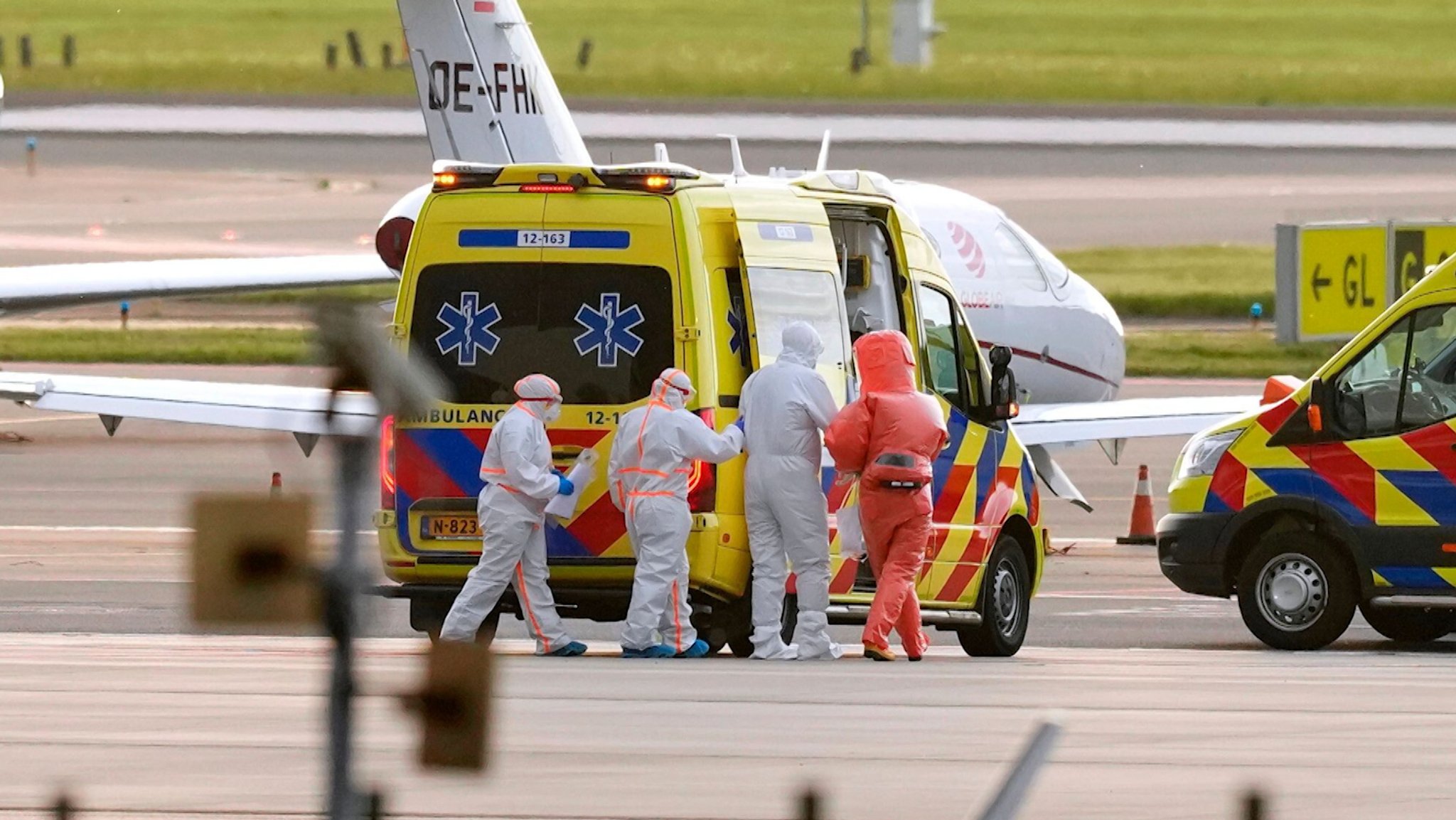 Personen in Schutzanzügen stehen bei einem niederländischen Krankenwagen auf einem Rollfeld | Bild: BR Personen in Schutzanzügen stehen bei einem niederländischen Krankenwagen auf einem Rollfeld