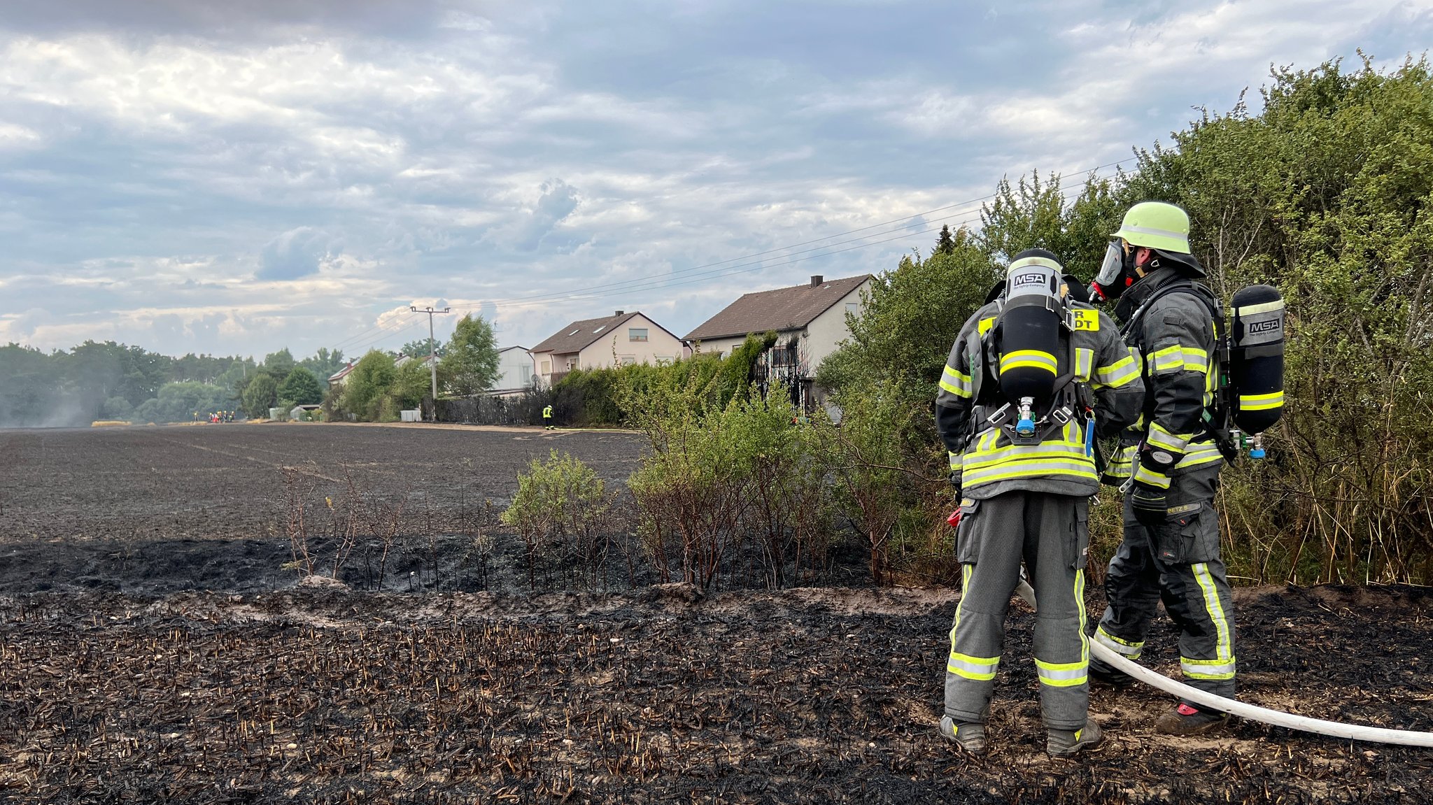 Feuerwehrleute bei Löscharbeiten auf einem Feld in Etzenricht