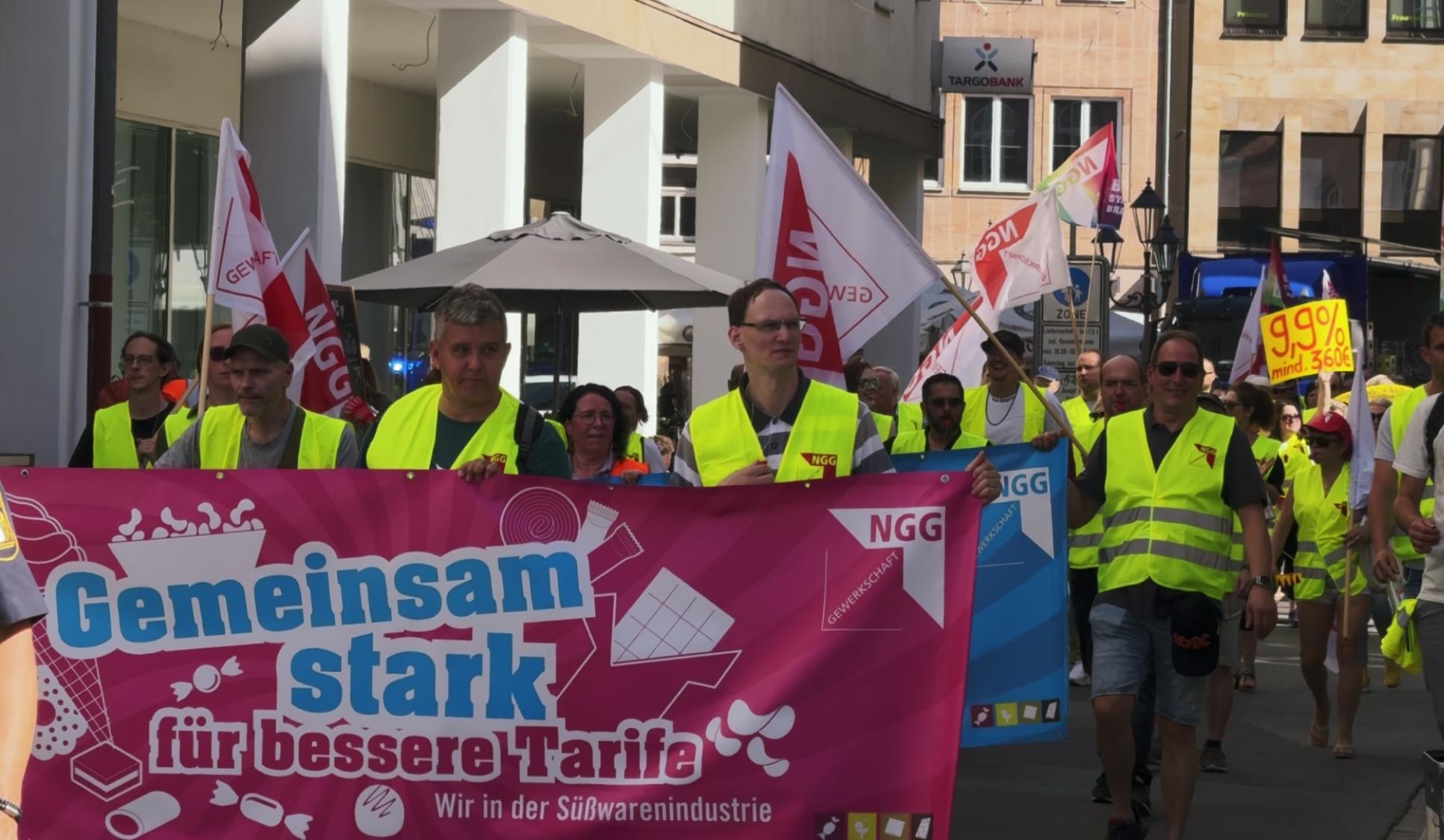 Demonstrierende der Süßwarenbranche halten Transparente hoch und ziehen durch Nürnberg. 
