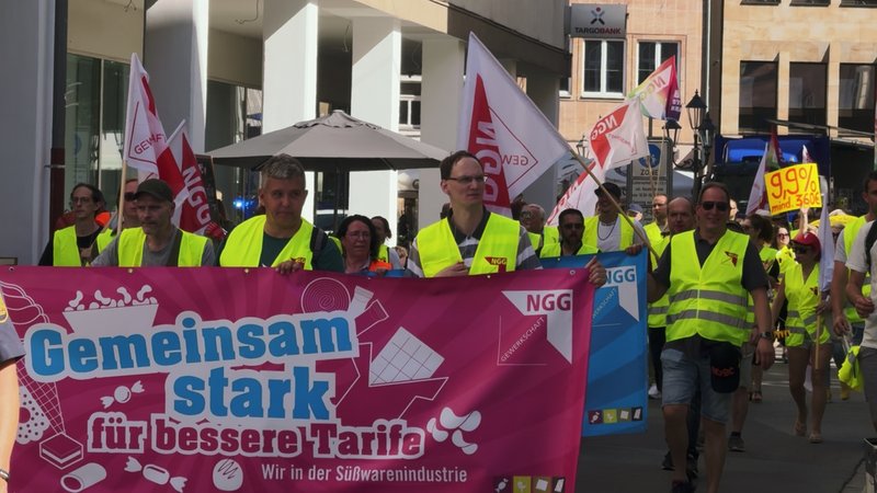 Demonstrierende der Süßwarenbranche halten Transparente hoch und ziehen durch Nürnberg. | Bild: BR24/Bettina Recum Demonstrierende der Süßwarenbranche halten Transparente hoch und ziehen durch Nürnberg.