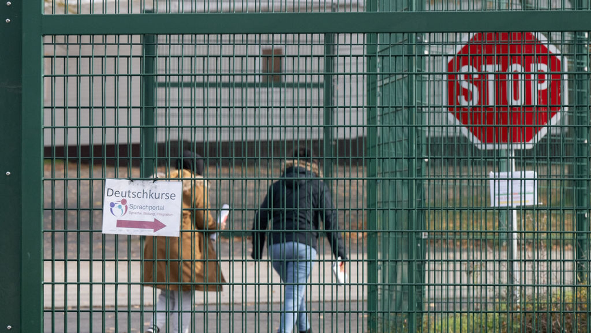 Symbolbild: Flüchtlinge gehen in der Erstaufnahmeeinrichtung (HEAE) in Gießen zu einem Deutschkurs. Im Hintergrund ist ein Stoppschild zu sehen.